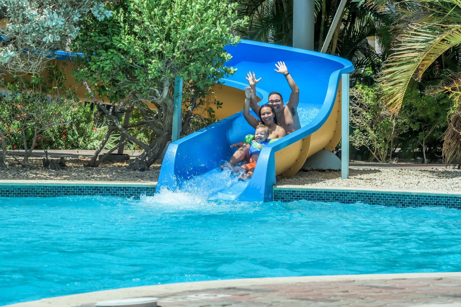 Two people are going down a water slide in a pool.