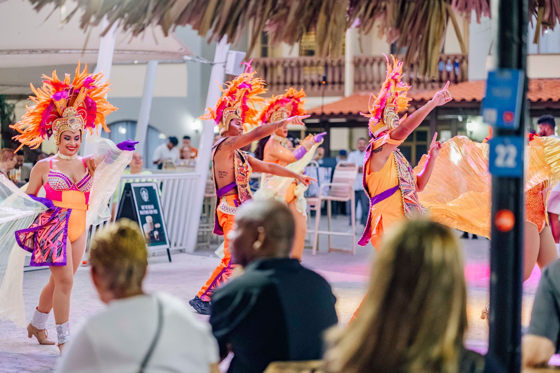 Dancers in colorful costumes perform outdoors at night; audience watches.