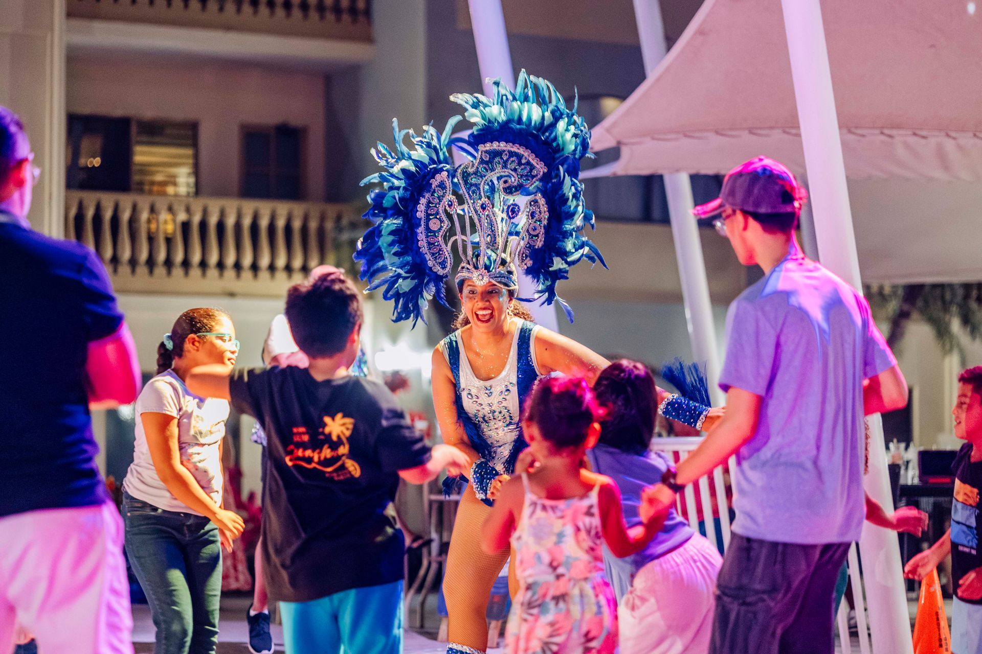 A person in a costume dances with children outdoors at night.