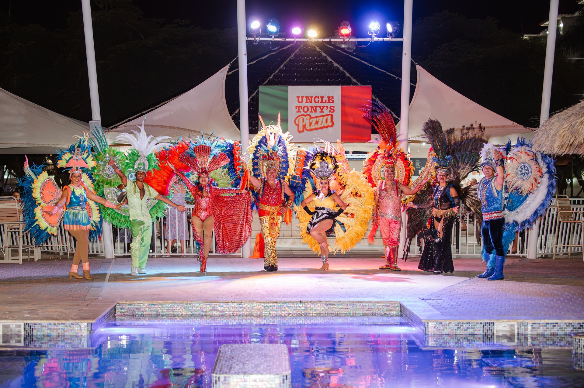 Group of costumed performers on a stage at night, possibly for a festival.