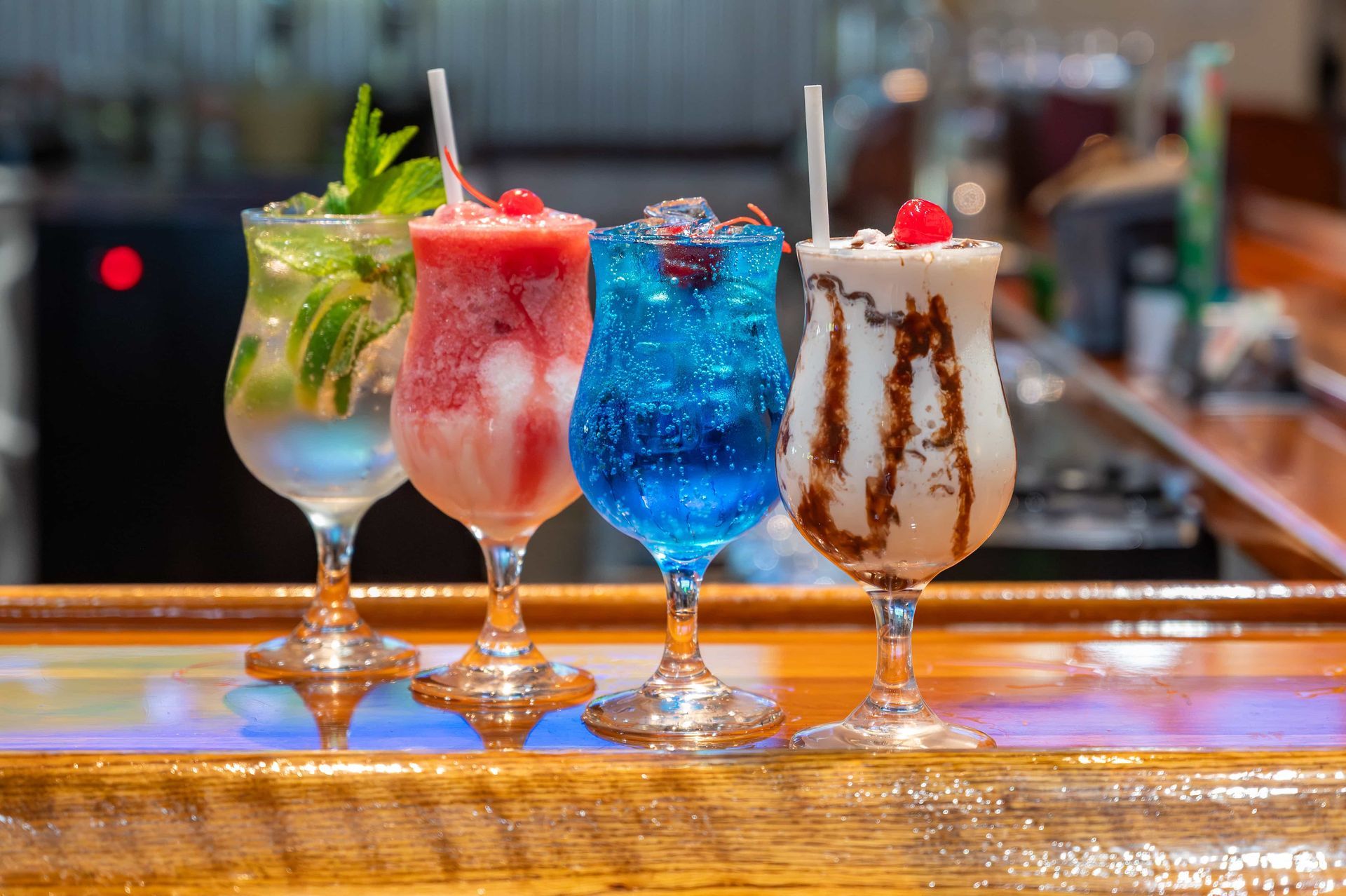 Four different types of cocktails are sitting on a bar.