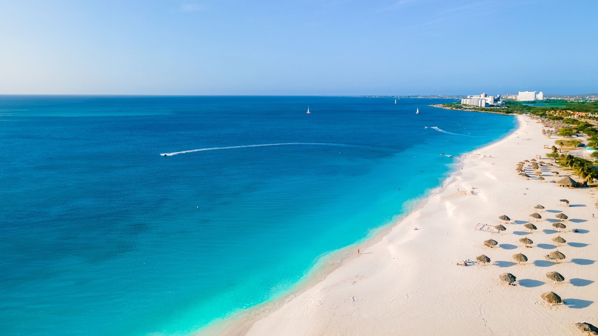 An aerial view of a beach with white sand and turquoise water.