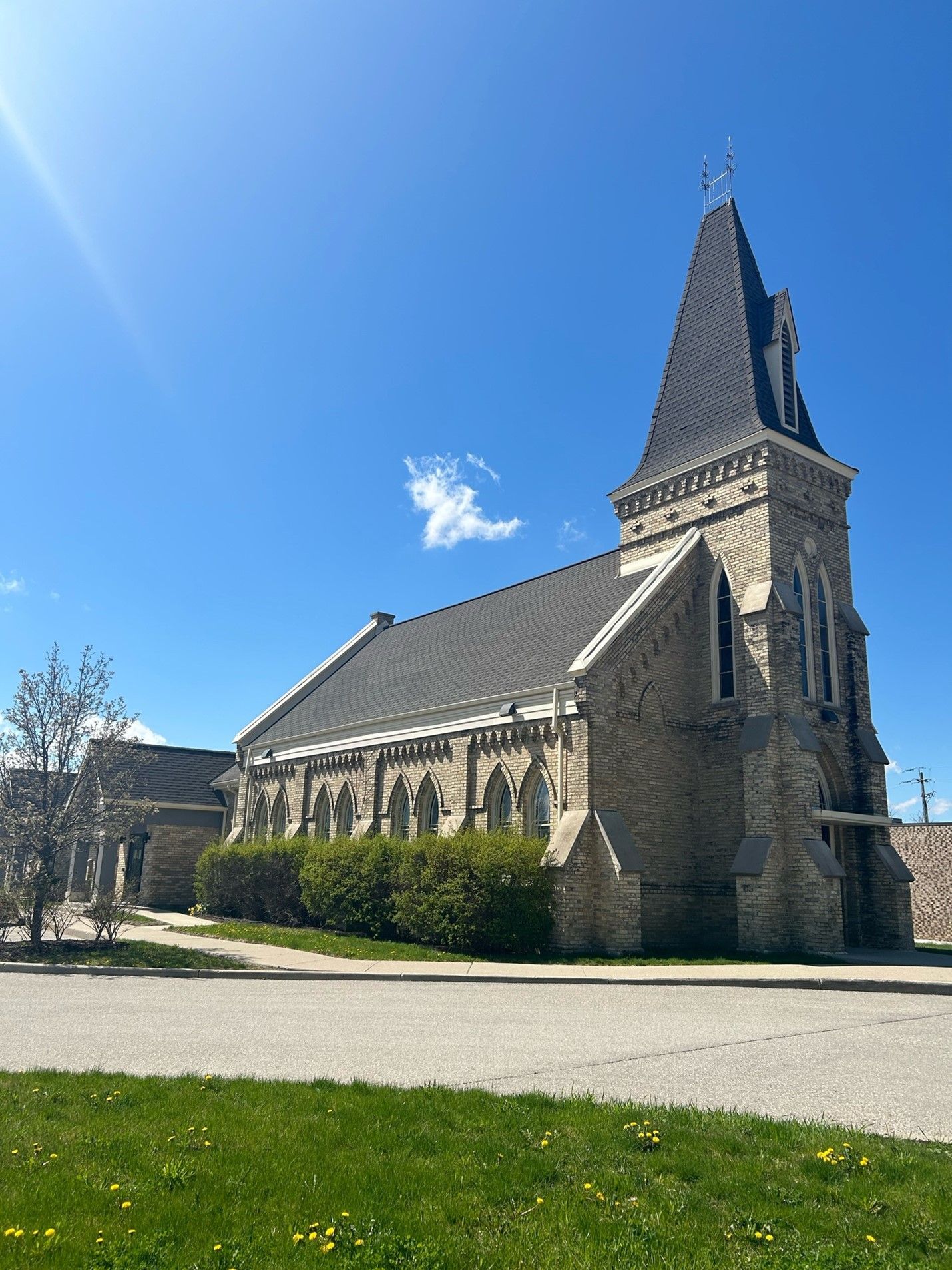 A large stone church with a steeple and a blue sky in the background.