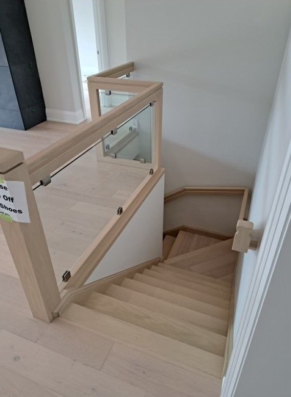 A wooden staircase with a glass railing in a house.