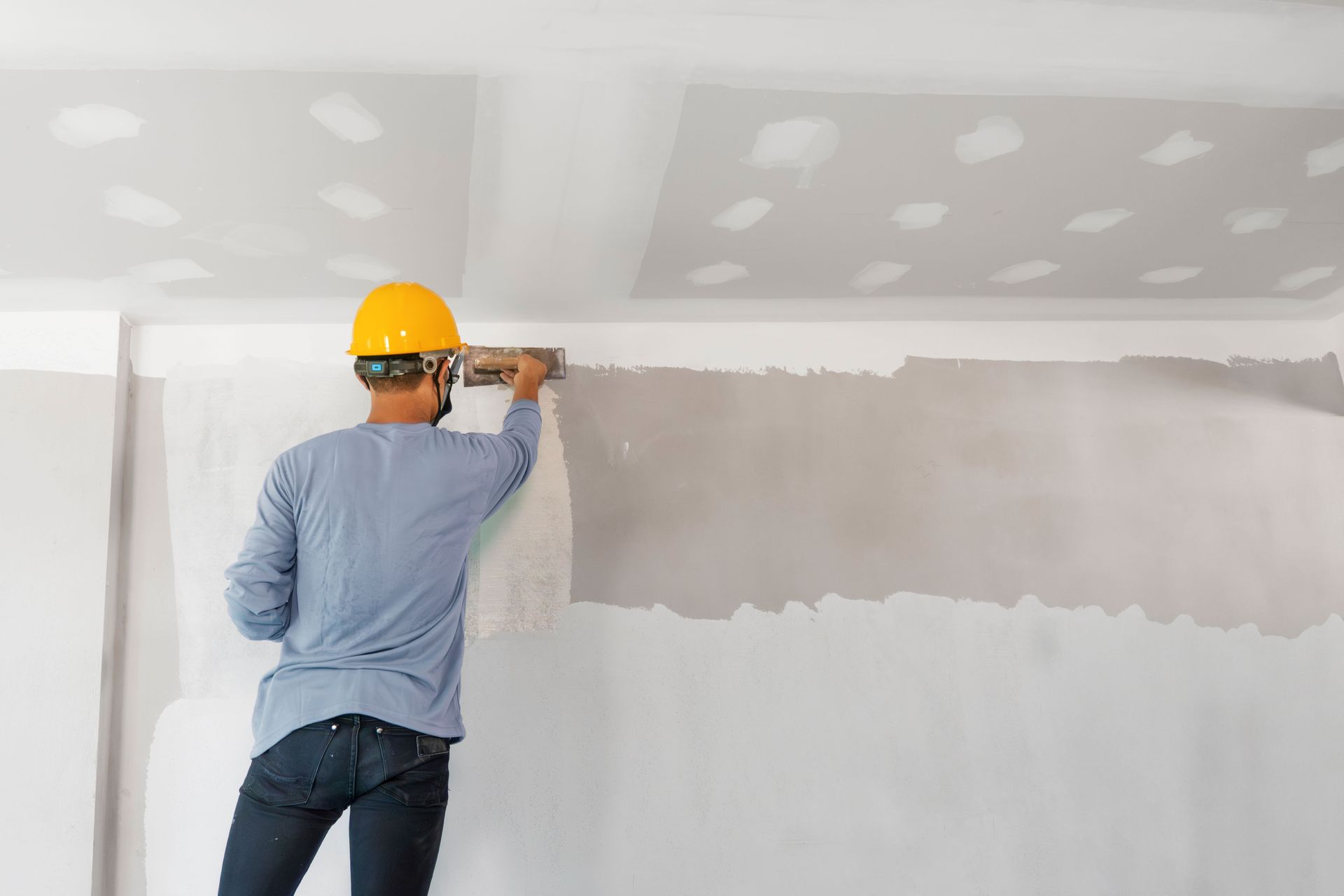 A man is plastering a wall with a trowel.
