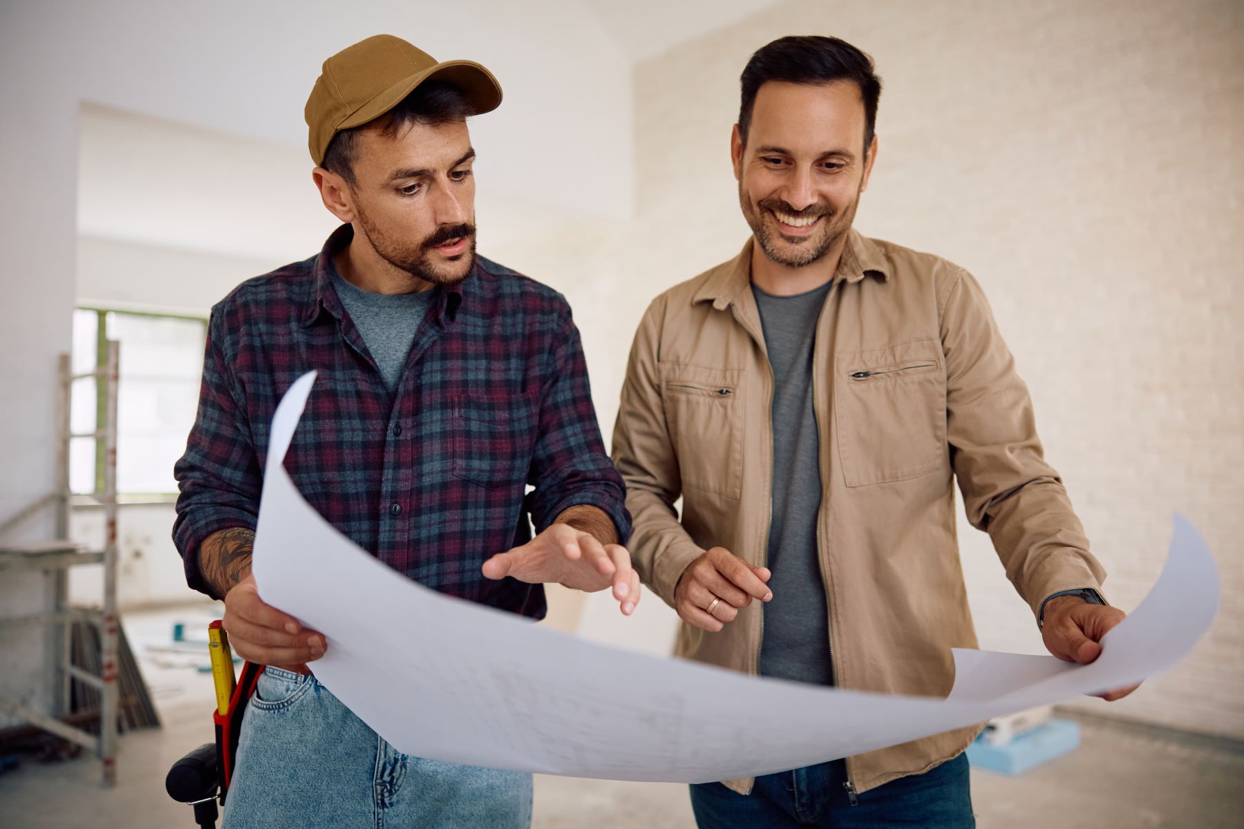 Two men are looking at a blueprint in a room.