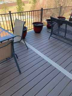 A deck with a table and chairs and potted plants on it.