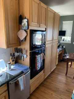 A kitchen with wooden cabinets , a refrigerator , a microwave , and a dishwasher.
