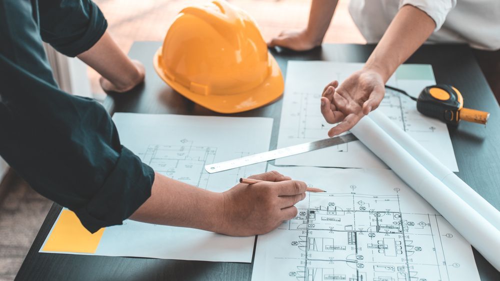 A group of people are sitting at a table looking at a blueprint.