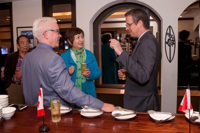 People conversing around a bar, drinks in hand. Canadian flags on the counter.