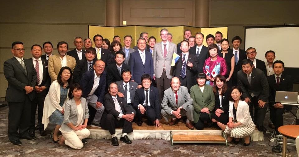 Group of diverse people posing for a photo in a hotel ballroom.