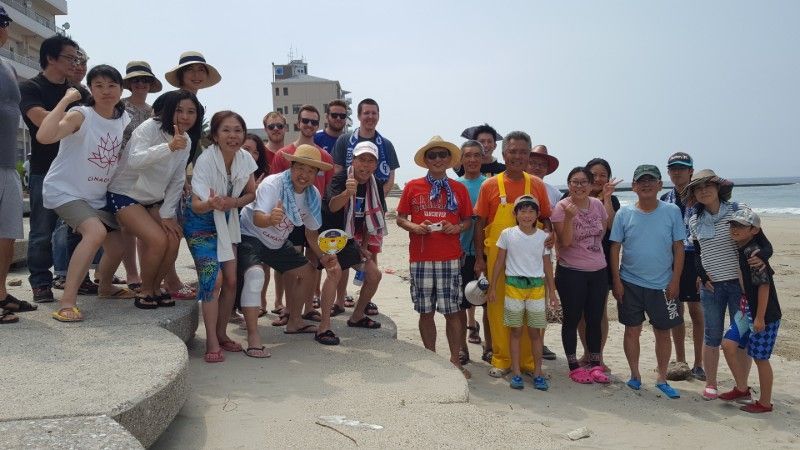 Group of people posing on a seaside promenade in bright sun, with the ocean in the background.