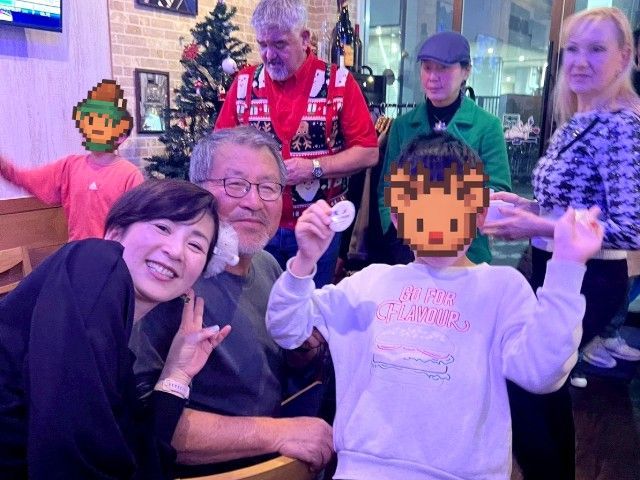 Group of people smiling, posing for a photo. A child and two others have pixelated faces. Festive setting.