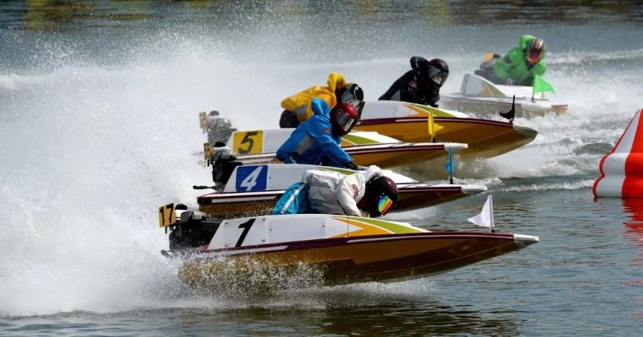Four powerboats racing on water, with white spray and red buoys marking the course.