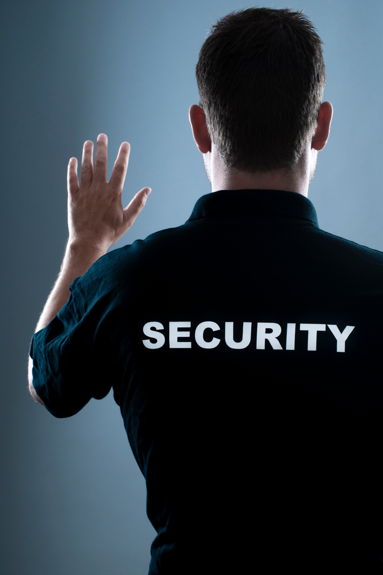 a man in a security uniform is waving his hand .