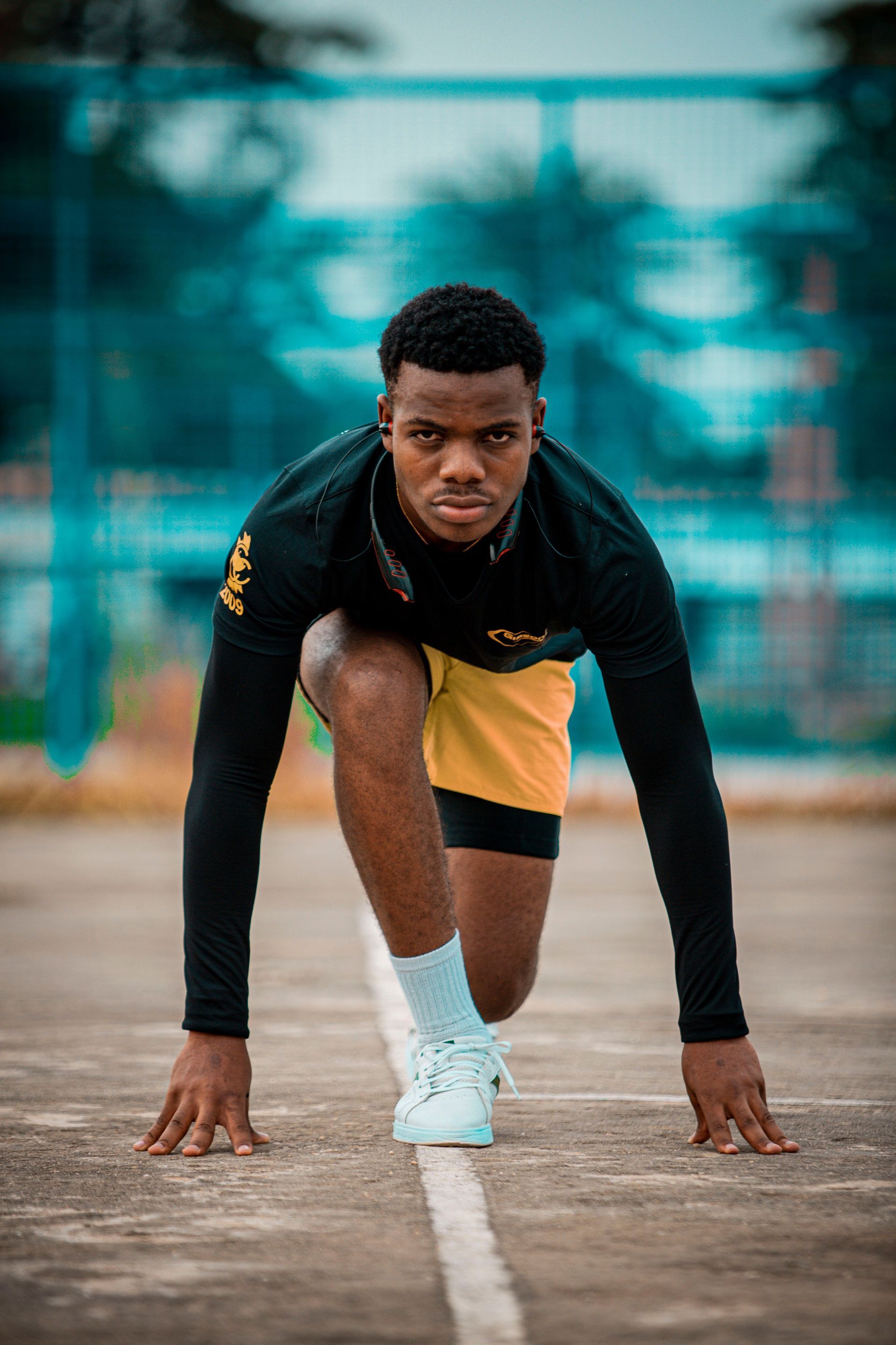 Athlete crouched at the starting line on a track, ready to sprint.