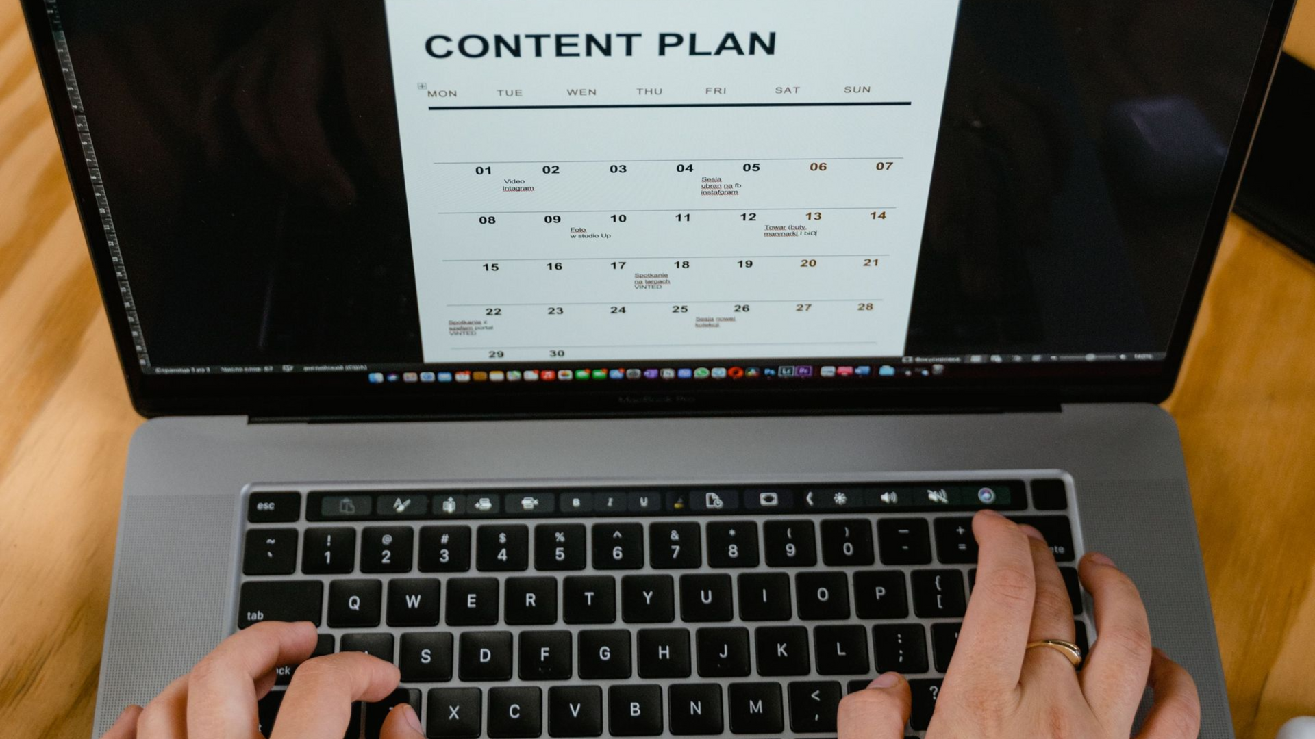 Hands on a laptop displaying a content plan document on a wooden desk.