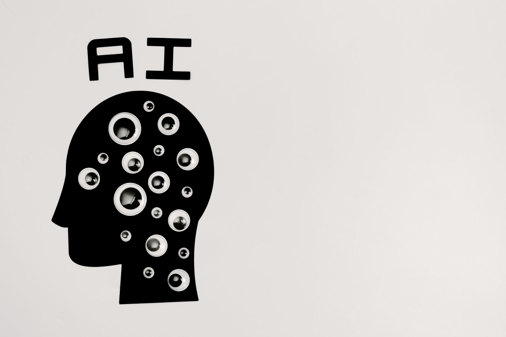 Black silhouette of a head with circuit-like circles and “AI” above it on a white background