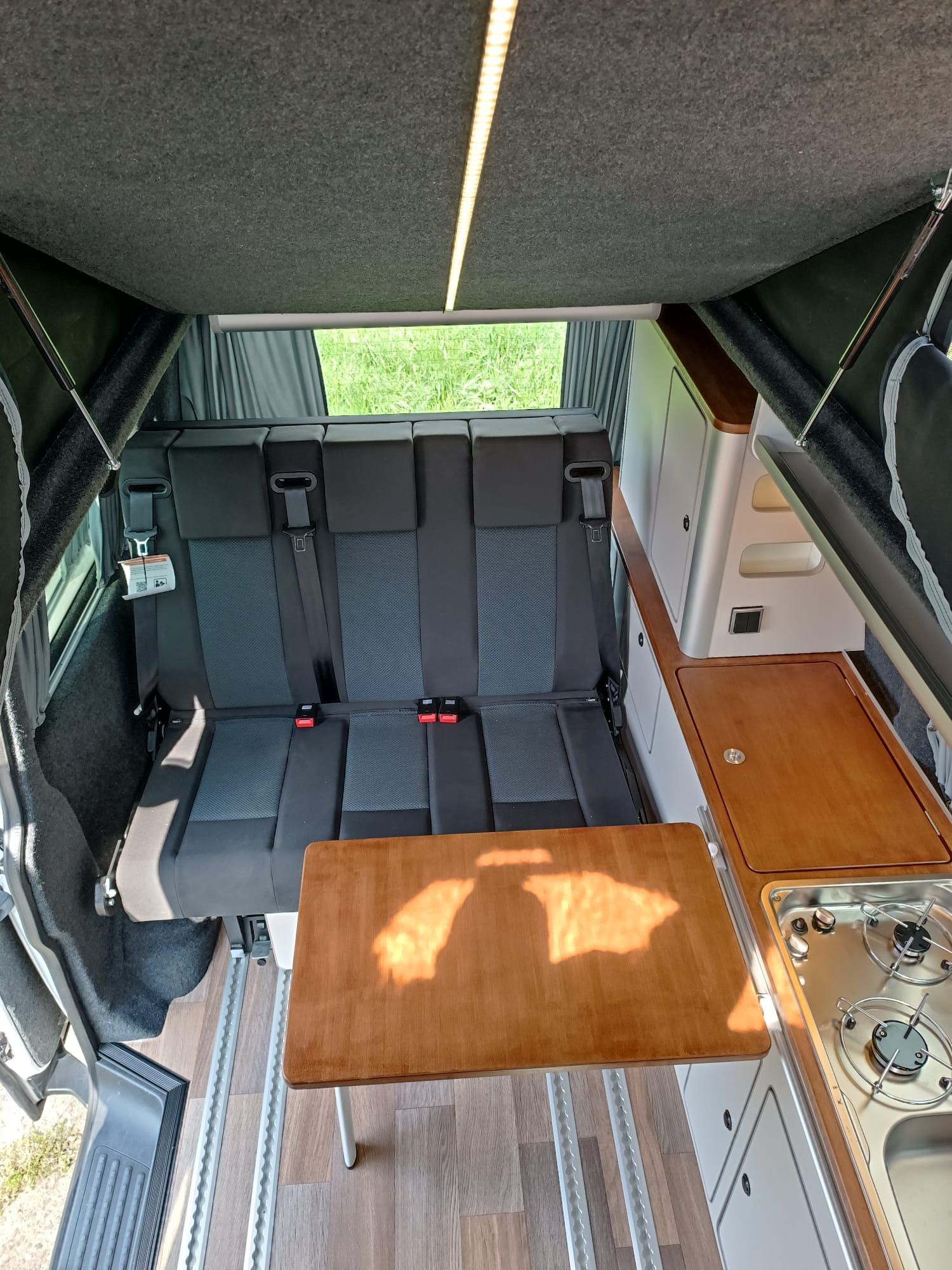 Interieur van een camper met een bank, tafel en keukenhoek.