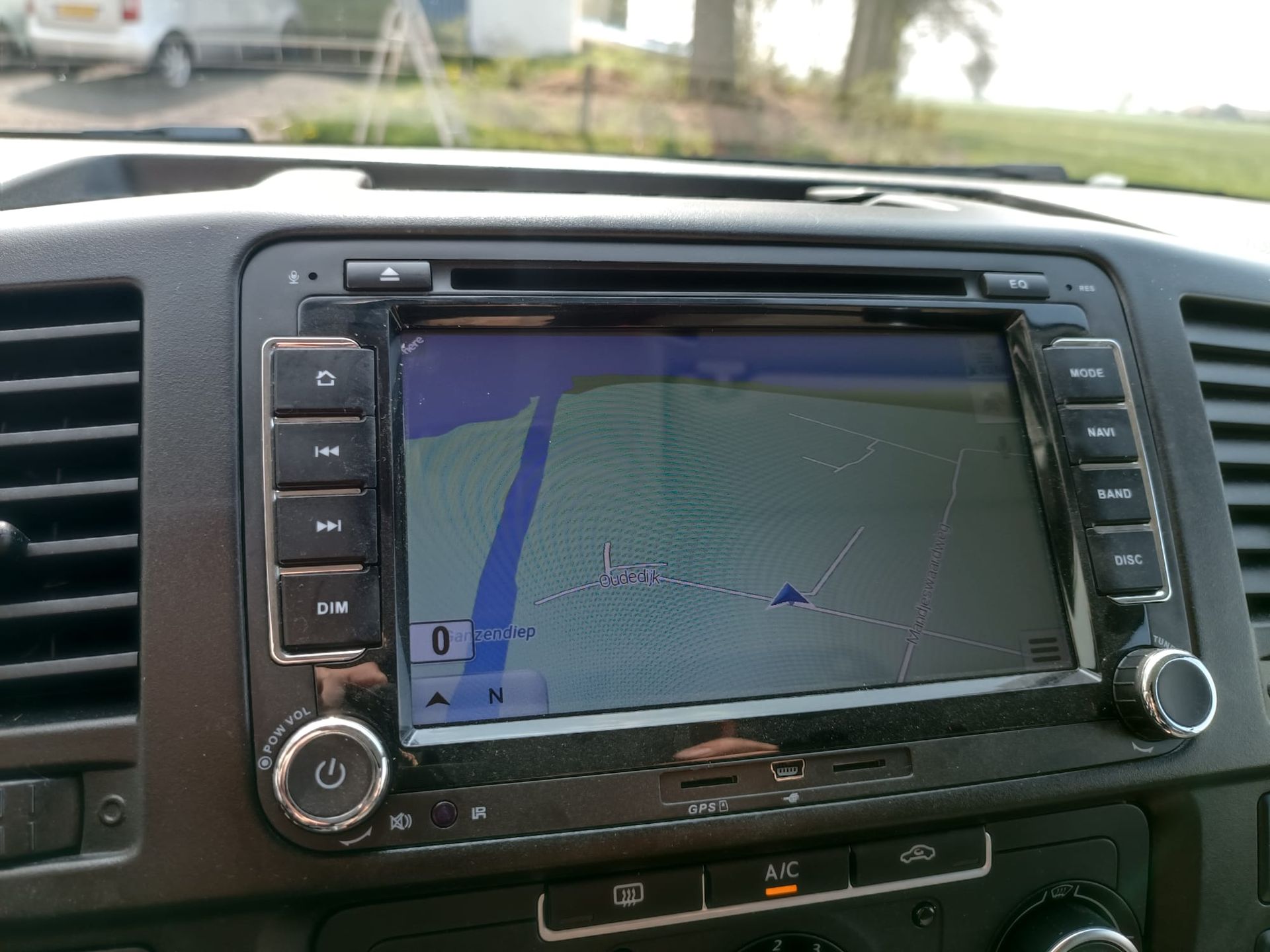 Dashboard van een voertuig met een scherm van een navigatiesysteem. Op het scherm wordt een kaart weergegeven in blauwe en groene kleuren.