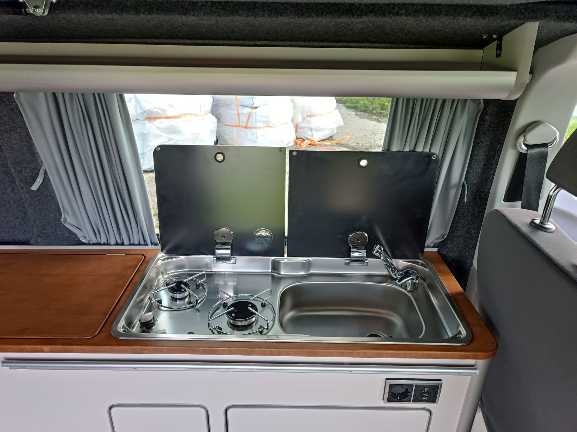 Interieurfoto van een camperkeuken met fornuis, spoelbak en inklapbare deksels.