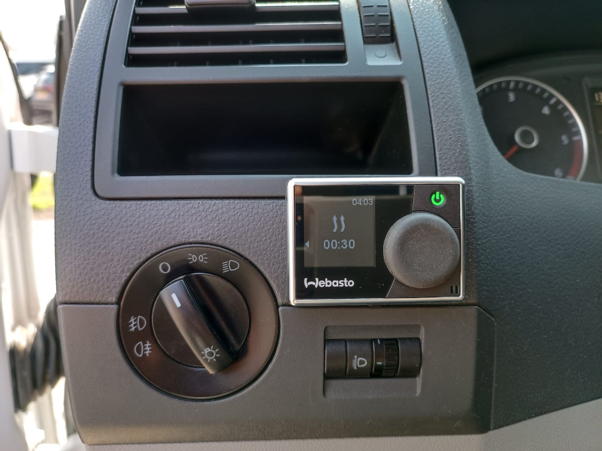Dashboard met Webasto-verwarmingsbediening en lichtschakelaar. Grijs interieur, zwarte bedieningselementen.