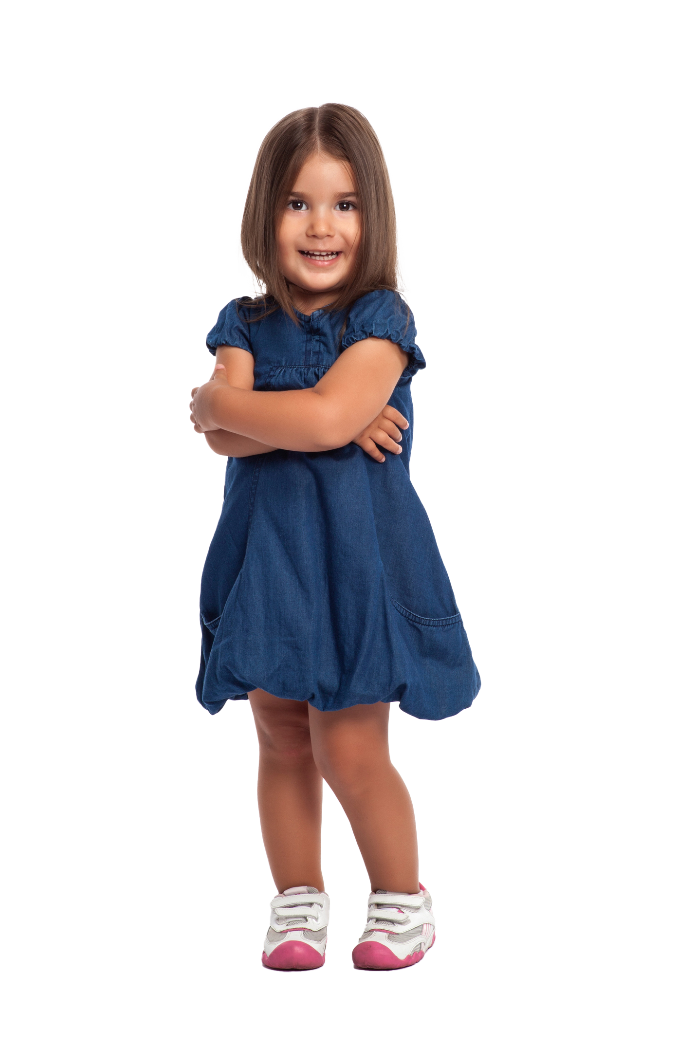 Girl smiling with arms crossed, wearing a blue denim dress and white shoes with pink accents.