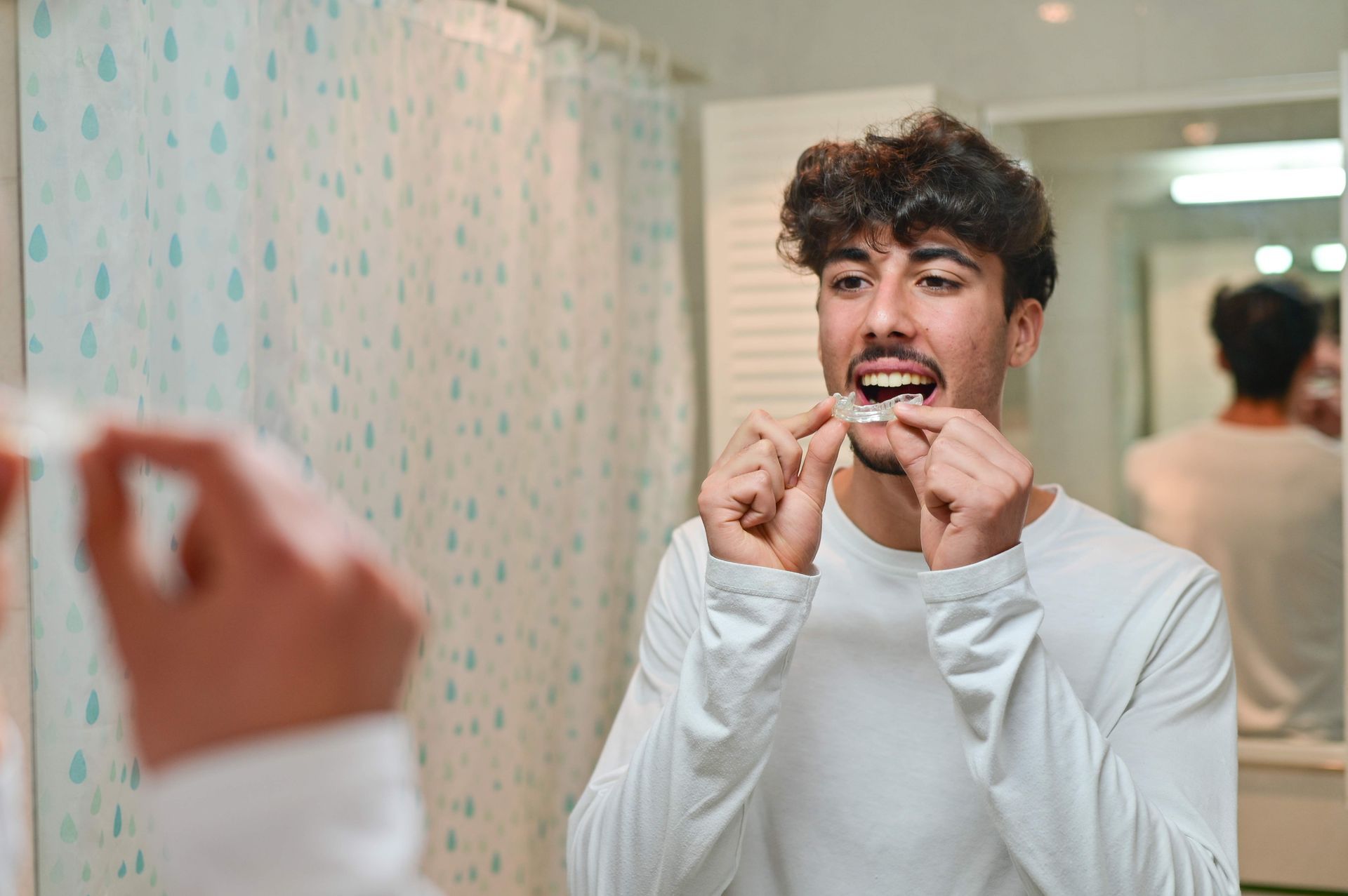 A man is looking at the mirror, putting on an overnight dental splint. A man is looking at the mirror, putting on an overnight dental splint.
