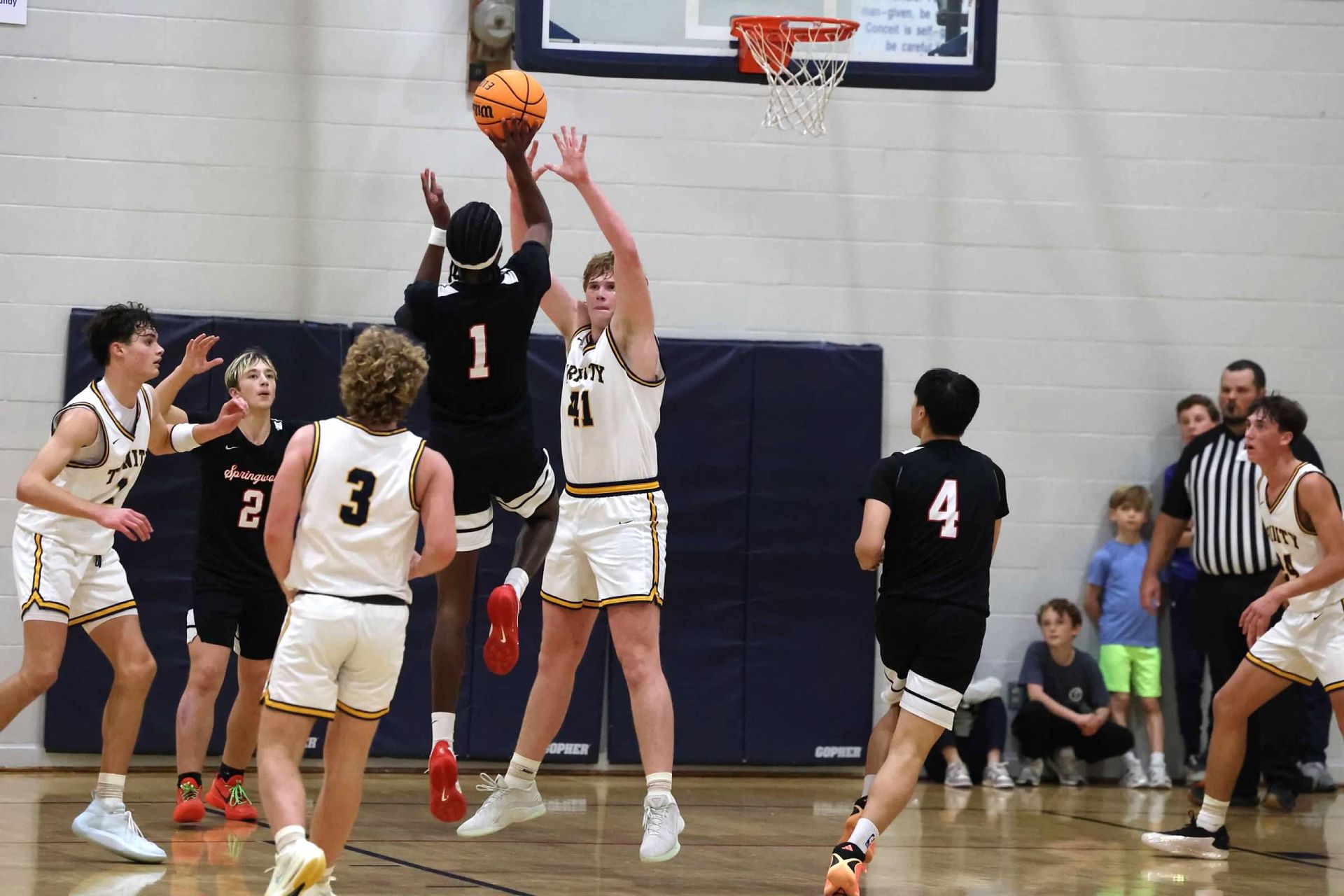 Basketball game with players leaping for a shot near the hoop in a gymnasium