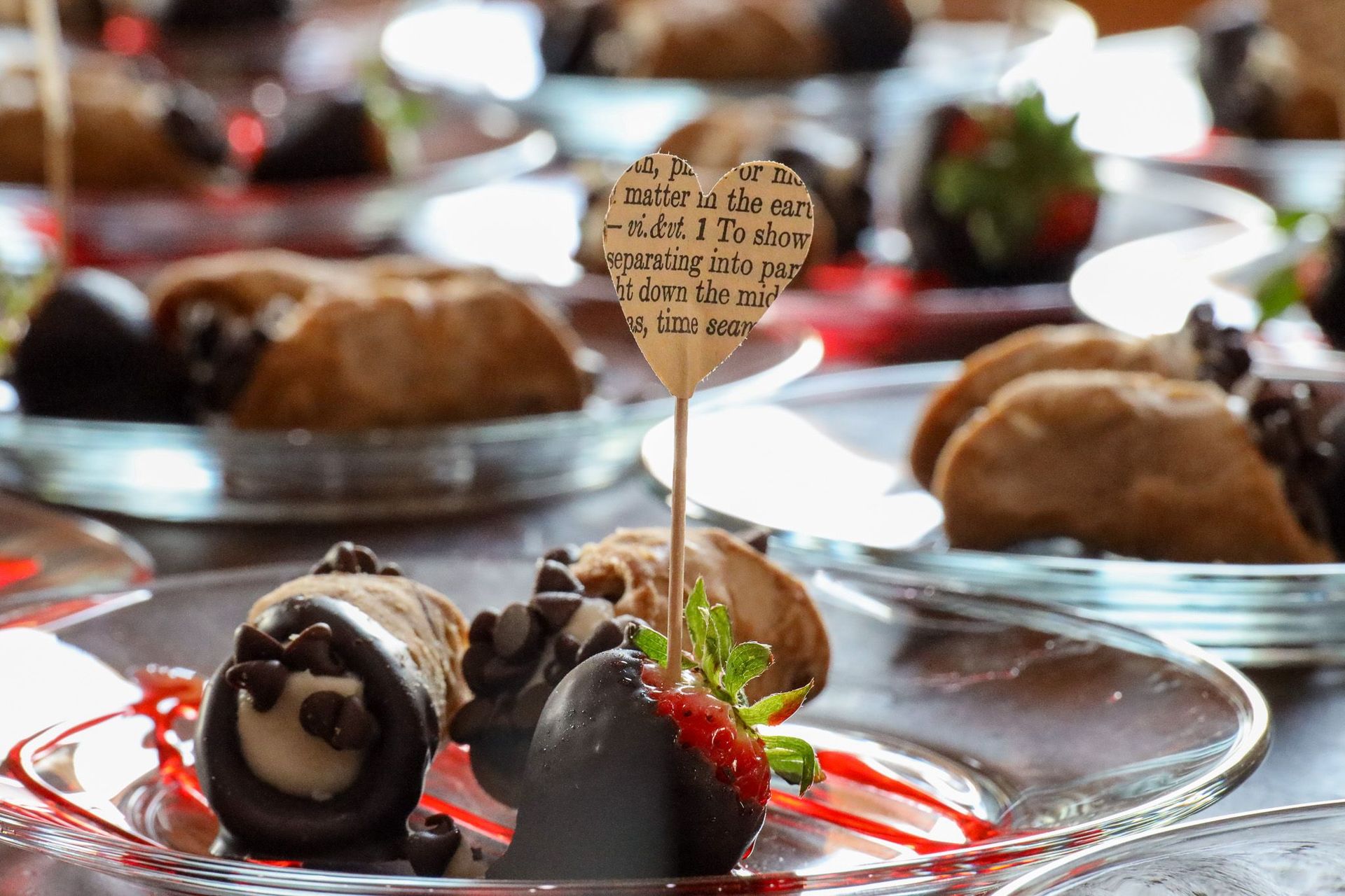 Tray of assorted desserts with chocolate-covered strawberries and pastries on glass plates