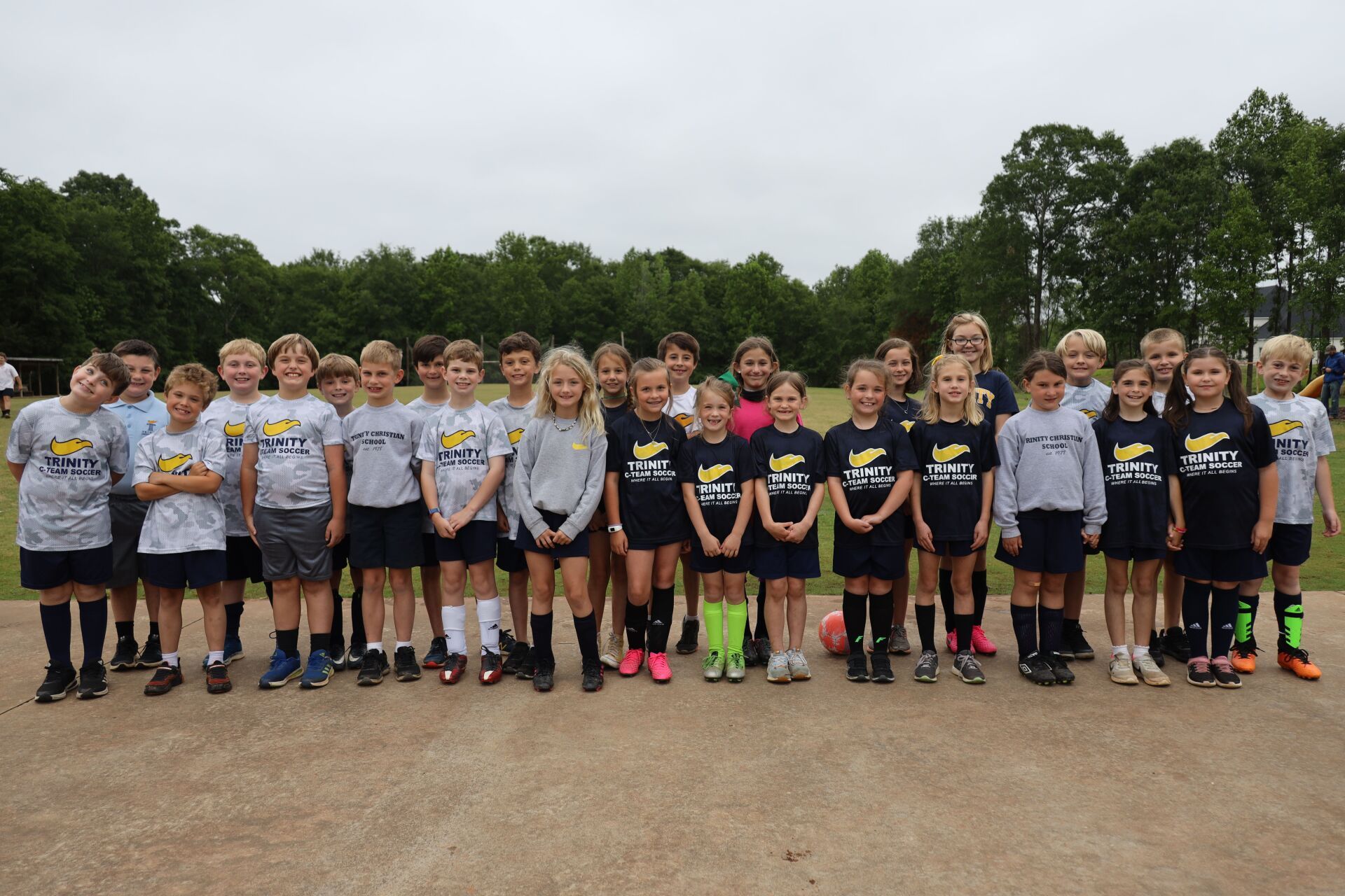 Youth soccer team lined up on a dirt field, wearing matching jerseys and neon socks.