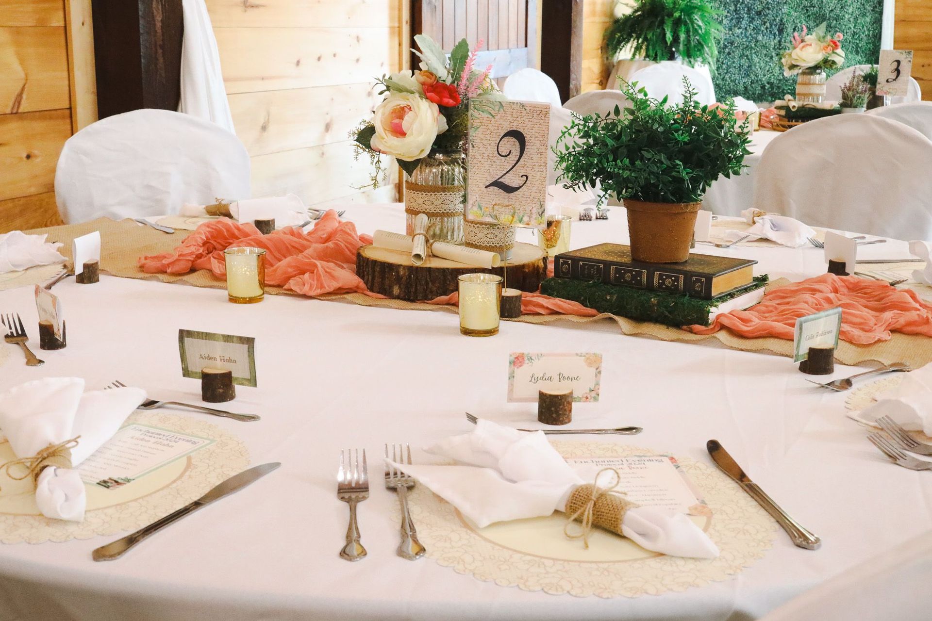 Elegant banquet table with white linens, floral centerpieces, and numbered table card 2