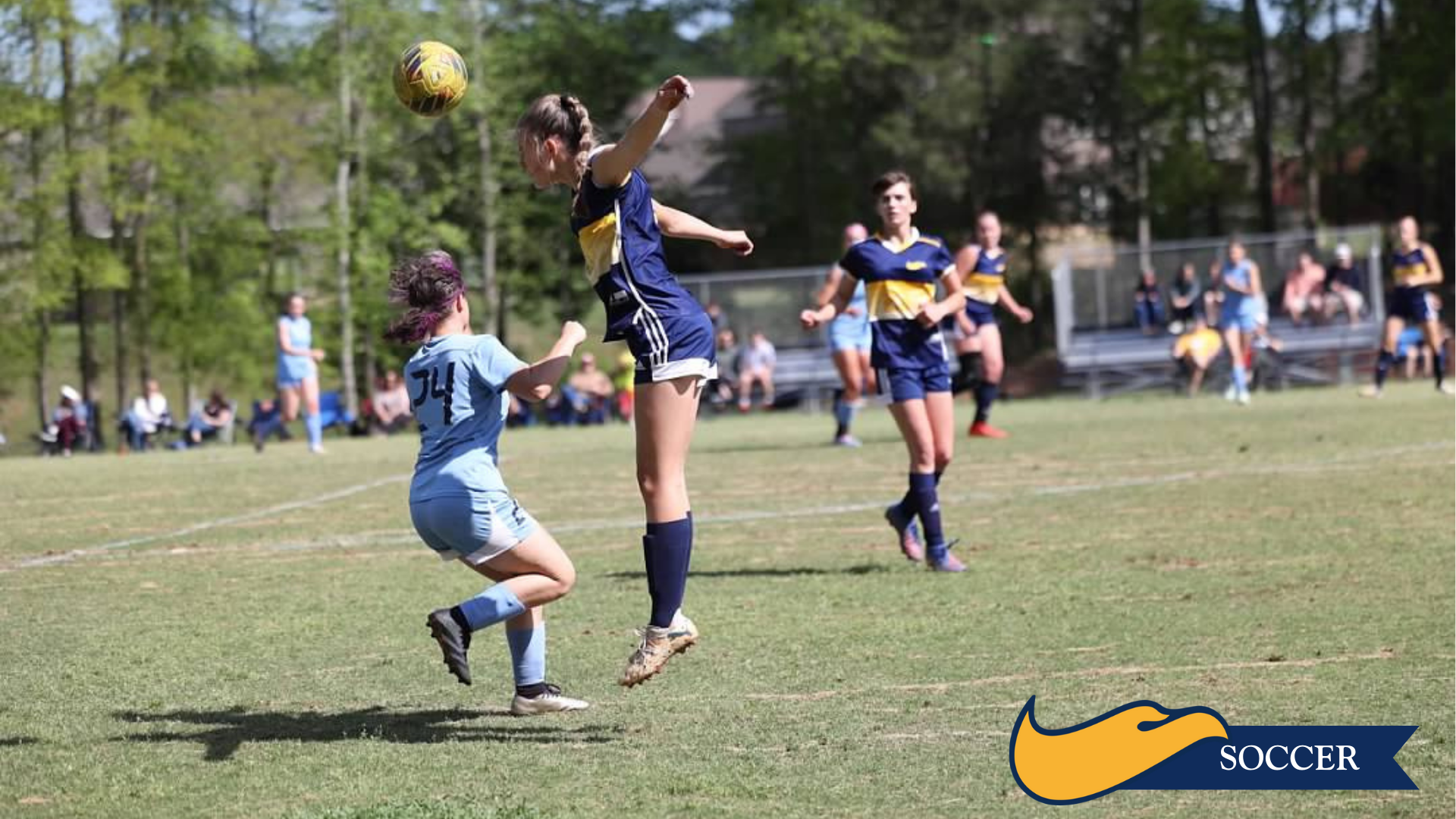 Soccer players contest a high ball on a grassy field during a match