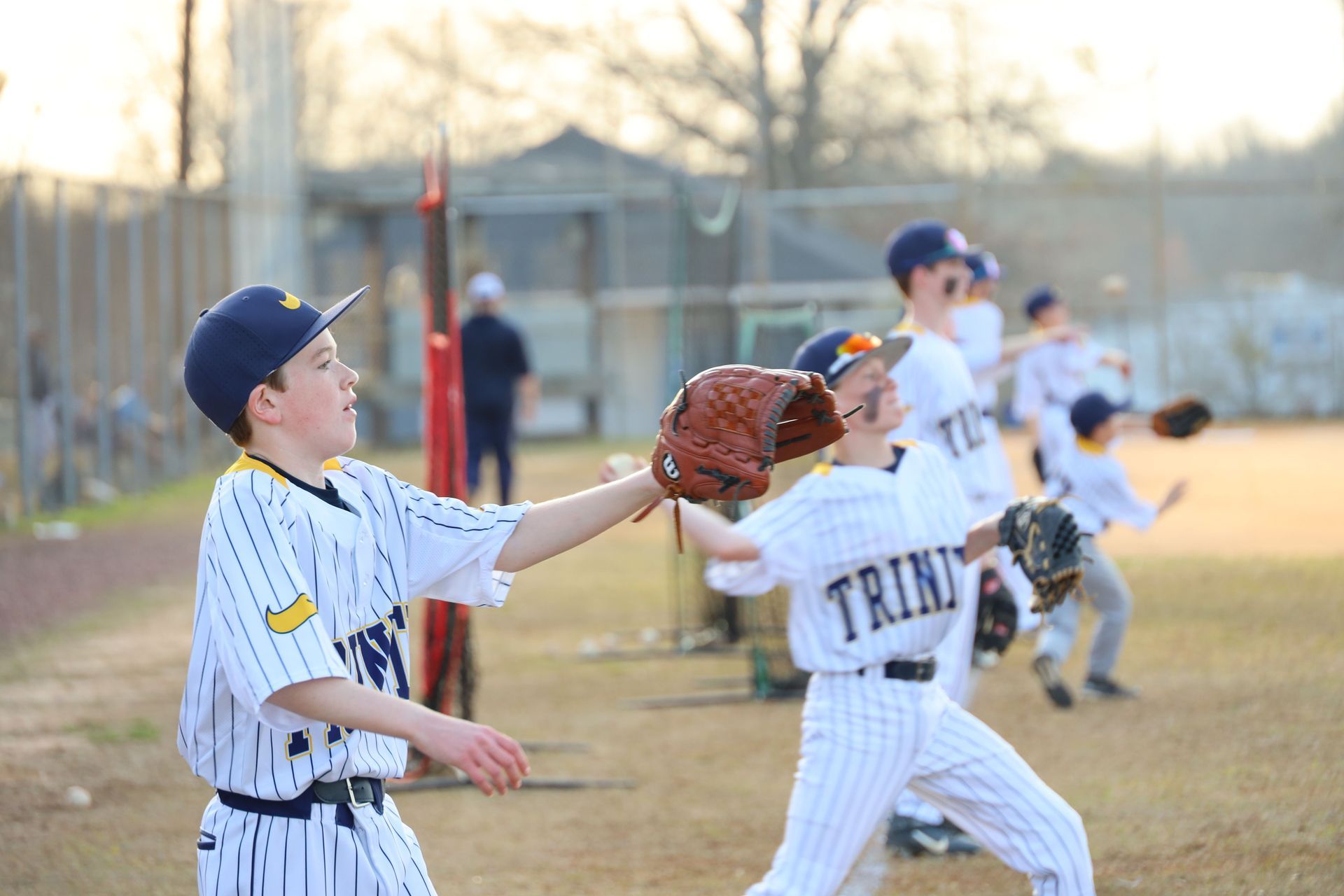 Youth baseball players practicing catching on a field at dusk