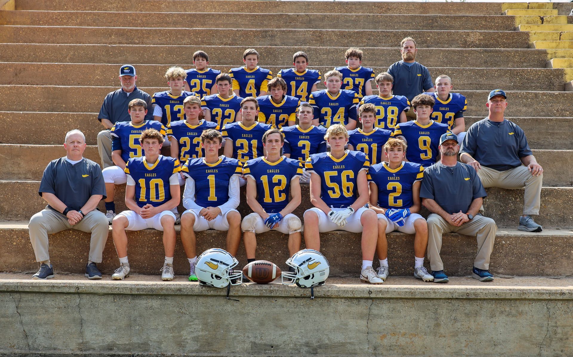 College football team in blue and gold uniforms posing outdoors on bleachers and steps