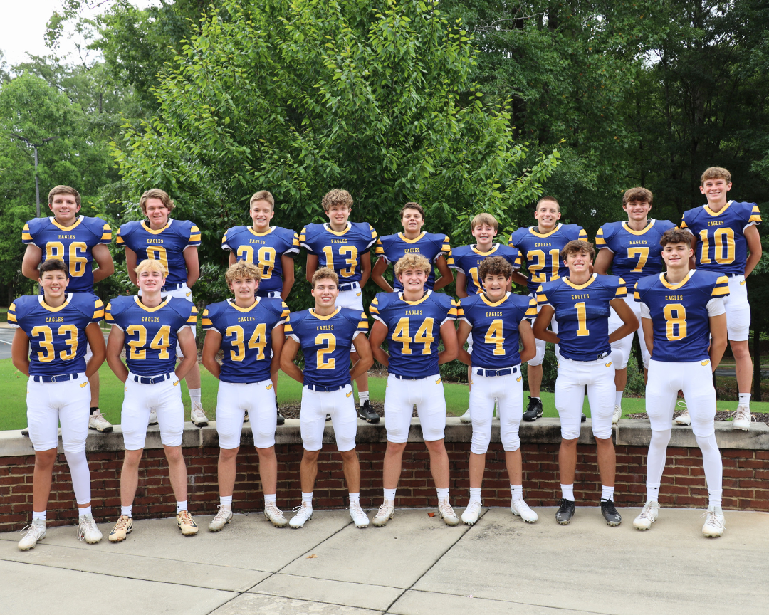 College football team in blue and gold uniforms posing outdoors on bleachers and steps