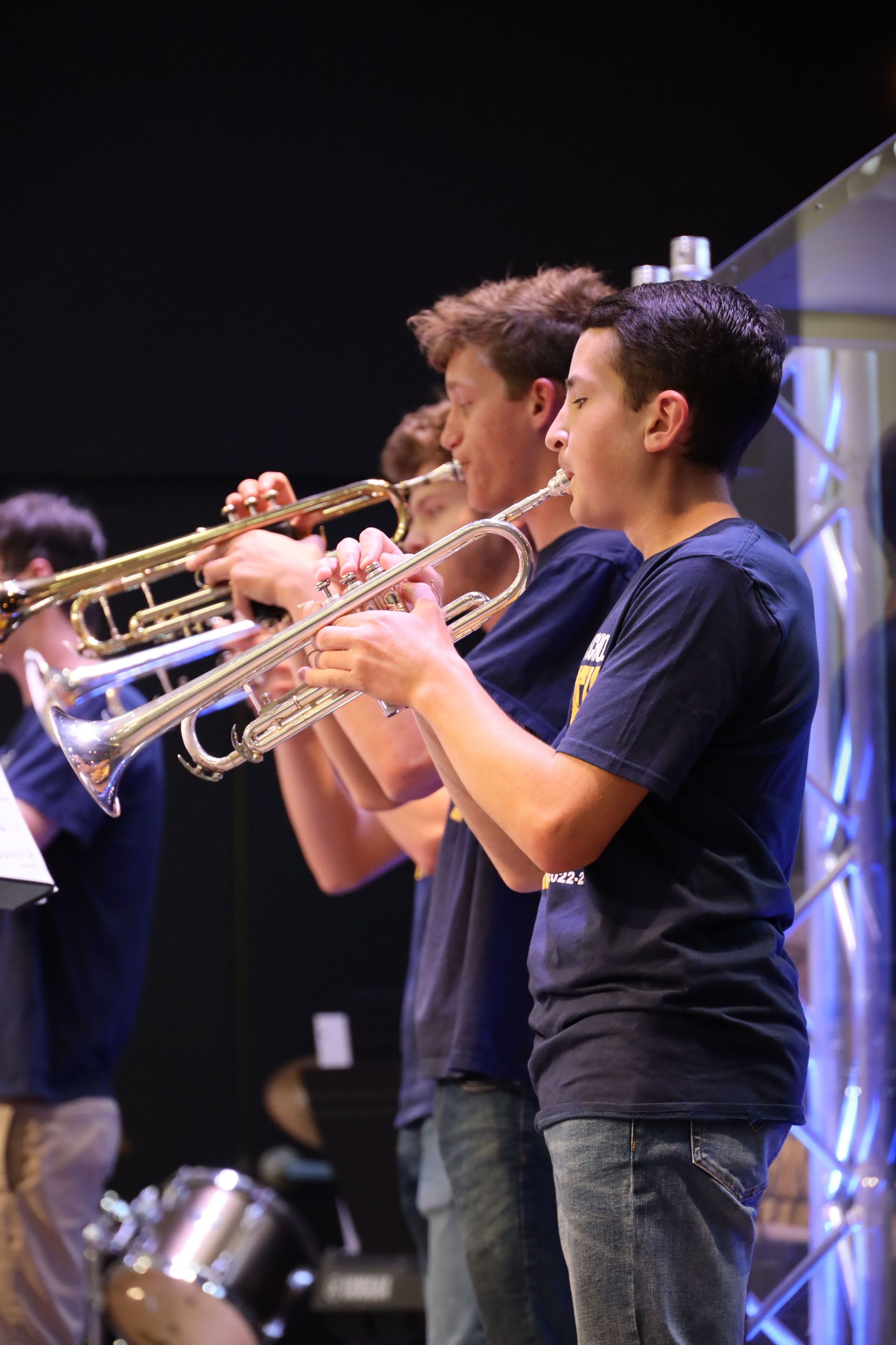 Two musicians playing trumpets on stage under purple lighting