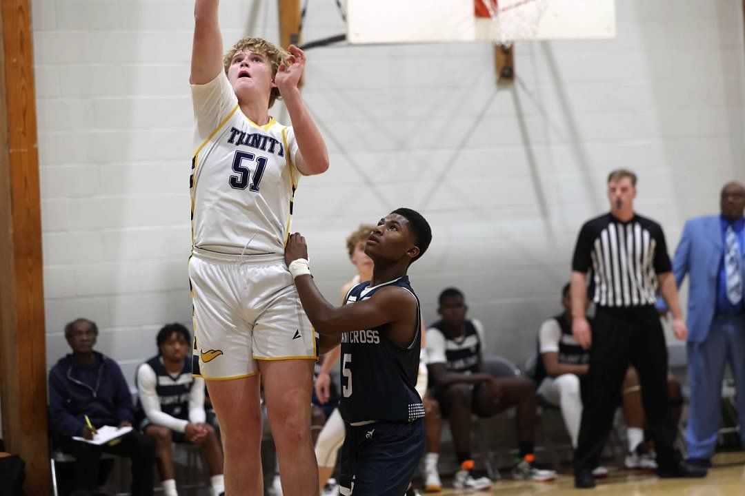 Basketball player in white shoots over a defender during an indoor game