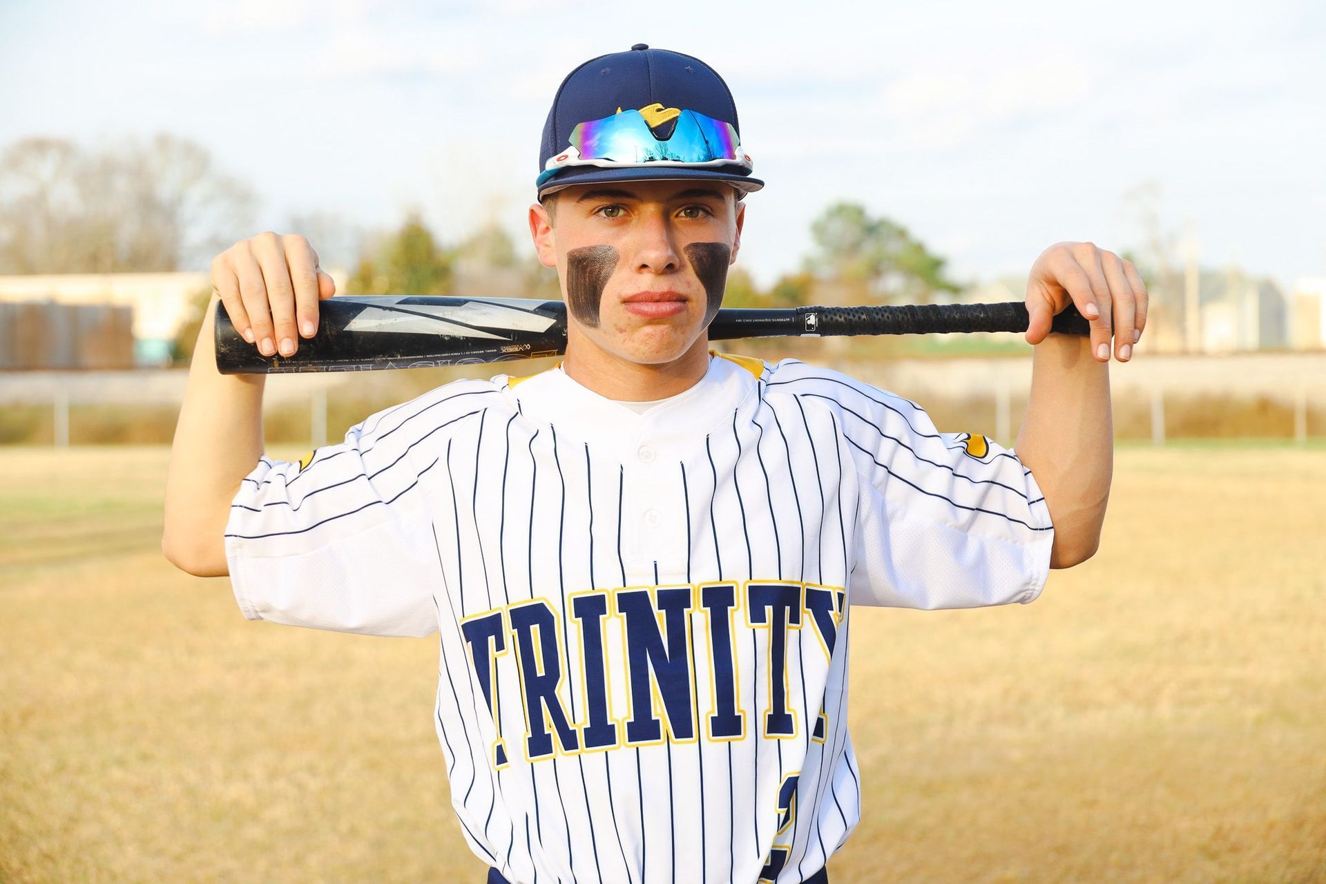 Baseball player in a Trinity jersey holding a bat on a field
