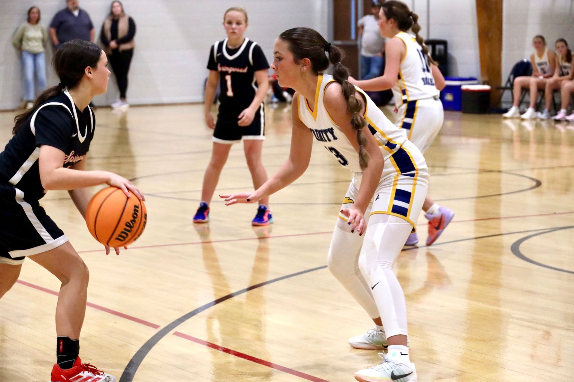 Youth basketball game with players dribbling and defending on an indoor court