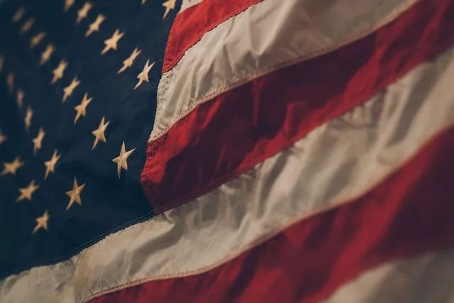A close-up of a wavy, textured American flag with its blue star field and red and white stripes.