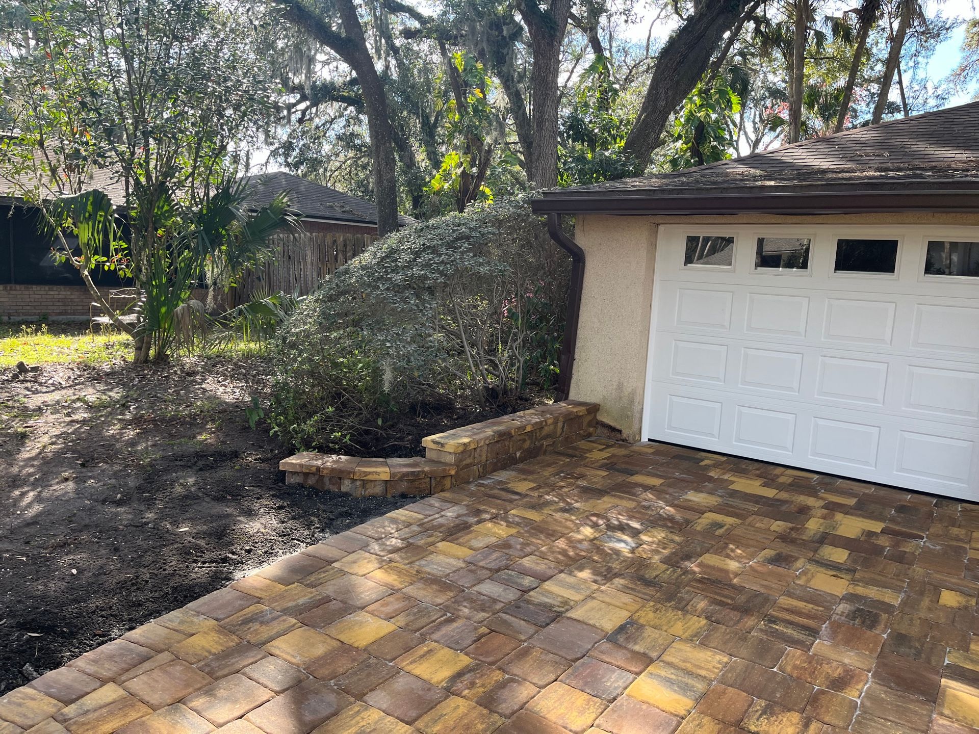 A white garage door is sitting next to a brick driveway.