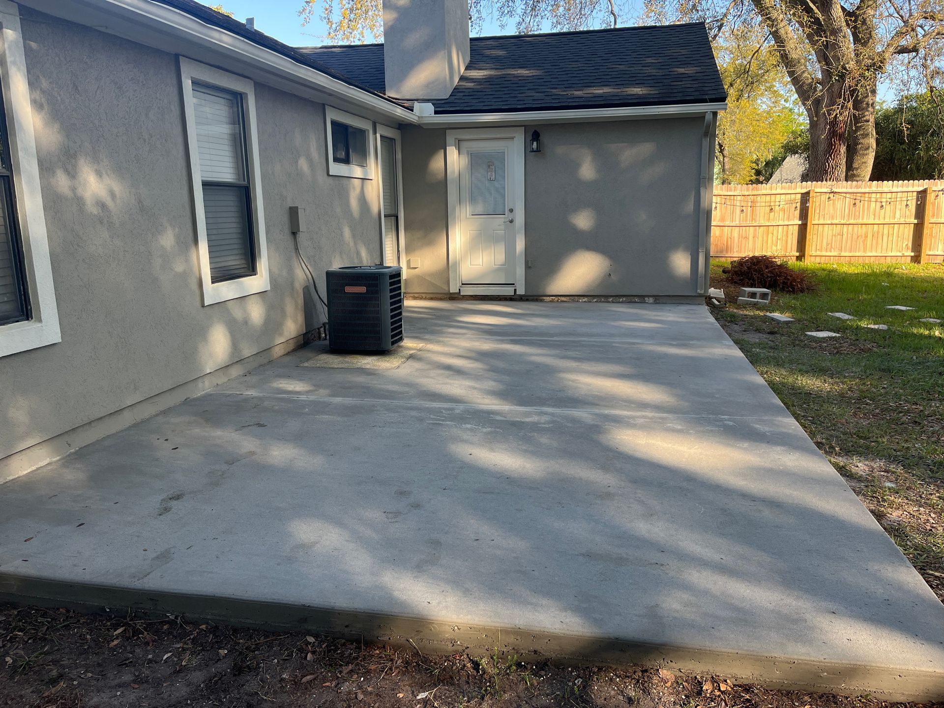 Sloped concrete entry beside garage wall and grass, poured by Outdoor Transformations in Flagler Estates, FL.
