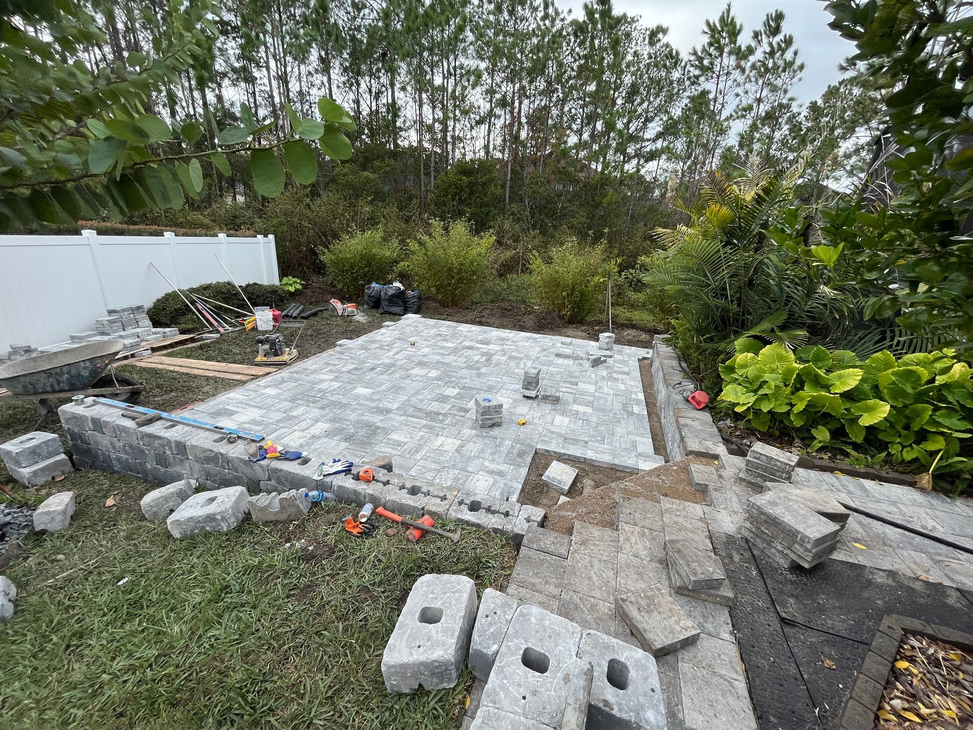 A paver patio project under construction in the backyard of a home in St. Augustine, FL, by Outdoor Transformations.