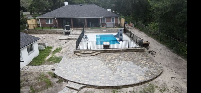 Curved paver patio with benches and steps around a pool in Jacksonville, FL