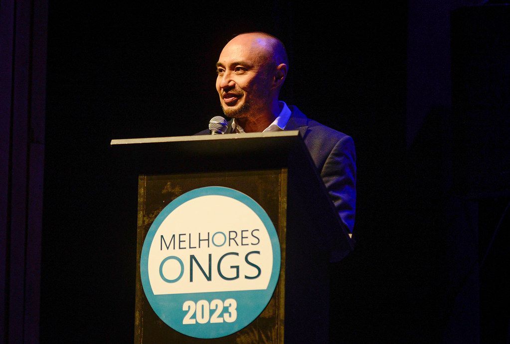 Homem discursando em um pódio com o logotipo 