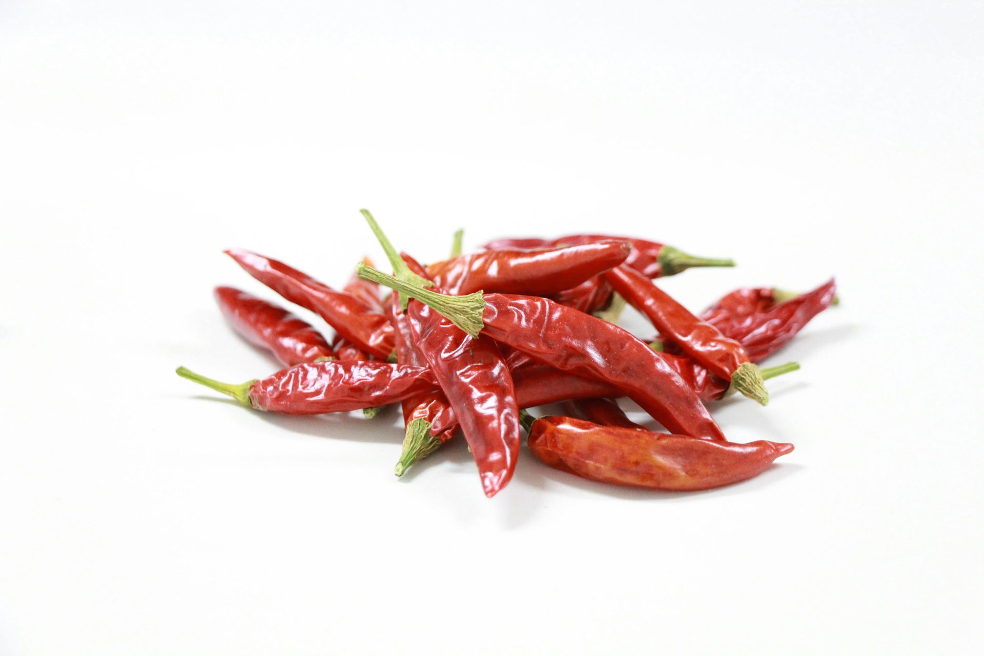 Stapel rode chilipepers op een wit oppervlak.