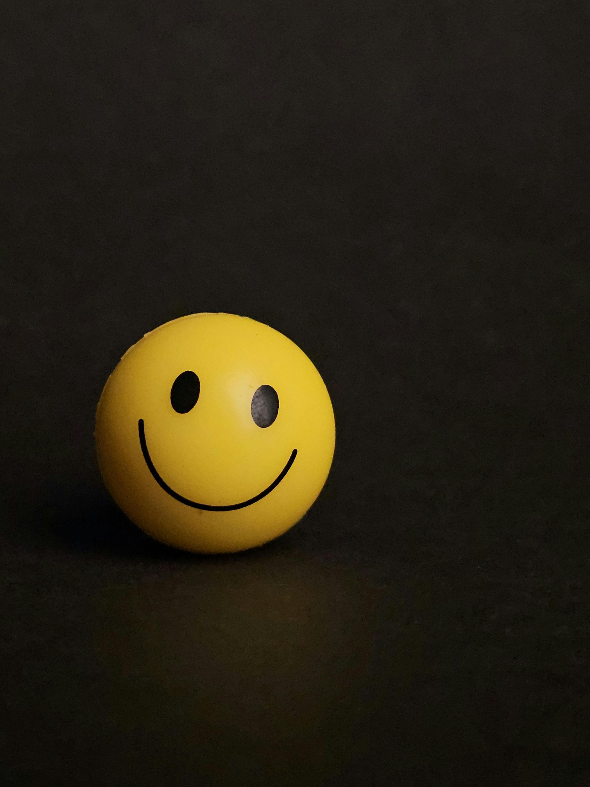 Gele smileybal op zwarte achtergrond.