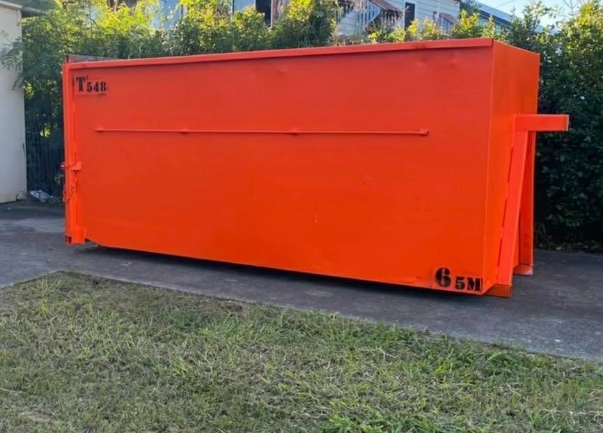 Bright Orange Dumpster on Concrete and Grass