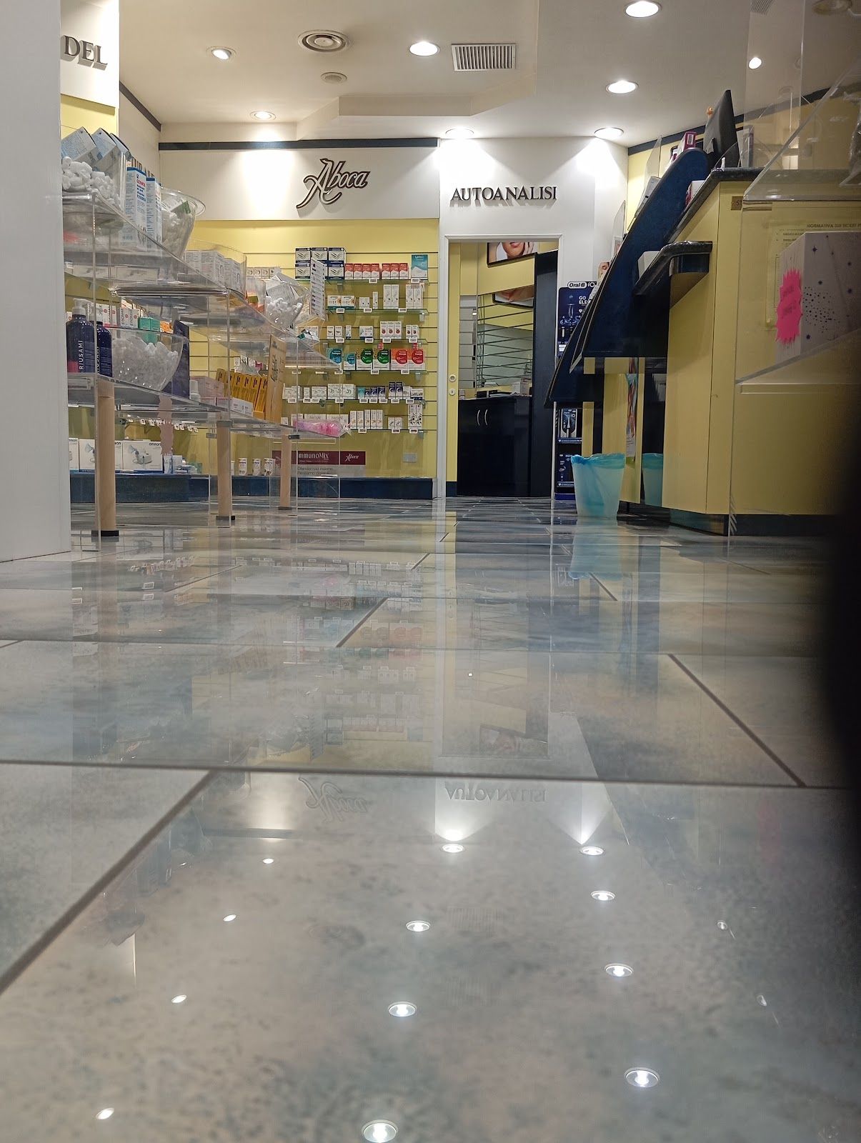Corridoio vuoto di un centro commerciale con pavimento piastrellato lucido e vetrine su entrambi i lati.
